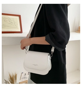 Detail of white PU leather saddle bag featuring 'FASHION TREND' print and silver metal hooks
