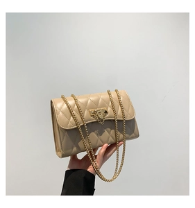 Detail shot of a beige quilted crossbody bag with golden clasp and chain strap
