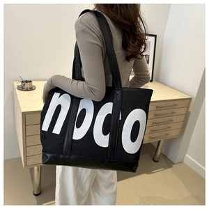 Detail of a large canvas tote bag with white npco lettering and leather handle