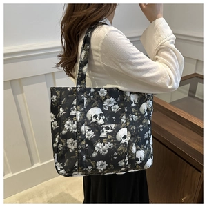 Side view of large black tote bag with skull and floral print on shoulder of a model