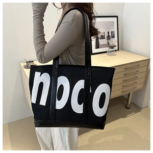 Side view of large black tote bag with white noco text on a female model