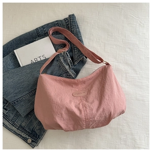 Detail of pink nylon tote bag with fashion label on white fabric next to denim jacket