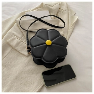 Detailed top view of a black flower-shaped crossbody bag on a beige jacket background