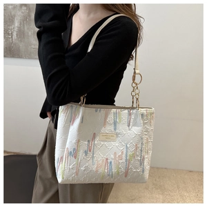 Détail macro d'un sac cabas en toile blanche avec broderies colorées et chaîne en métal
