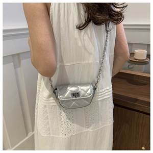 Mini sac selle argenté matelassé avec bandoulière chaîne porté sur robe en dentelle