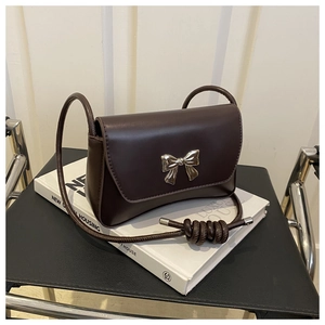 Détail du nœud argenté sur le sac à bandoulière en cuir marron foncé lisse avec nœud