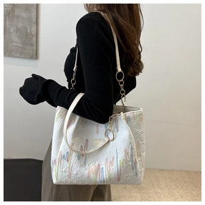 Détail du cabas blanc texturé avec broderie ondulée colorée et bandoulière en chaîne dorée