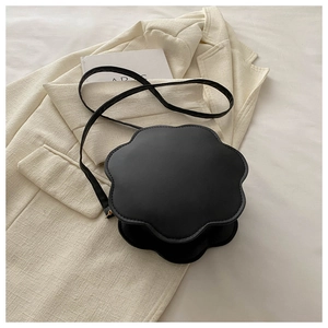 Detail of a black floral-shaped leather crossbody bag on a textured beige blazer