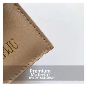 Close-up of beige lychee textured leather with golden logo and precision stitching