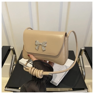 Détail du sac baguette beige avec nœud argenté décoratif et fine bandoulière élégante