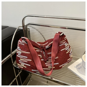 Detailed texture of dark red rhythmic stripe embroidery on a soft canvas dumpling bag