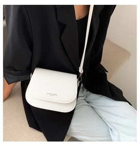 Detailed view of a white minimalist saddle bag with Fashion Trend text on a crossbody model