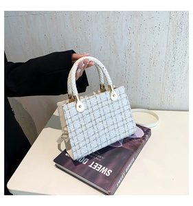 Detail of cream tweed handbag with gold texture, woven handle and gold-tone hardware