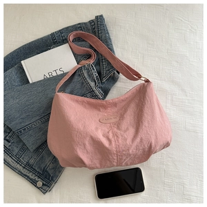 Detailed close-up of pink nylon shoulder bag with Fashion label on textured background