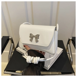 Détail d'un sac à bandoulière en cuir blanc avec boucle nœud argentée et bandoulière nouée