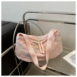 Detailed close-up of pink textured canvas bag with colorful stitching and woven zipper pulls
