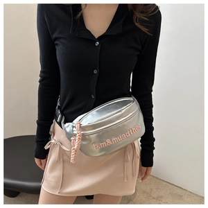 Detail of silver metallic crossbody bag featuring pink embroidered logo and woven zipper pull