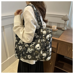 Large gothic tote bag featuring white floral skull patterns and durable black straps