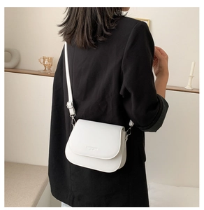 Detailed view of the white saddle bag with adjustable strap worn by a model in a room