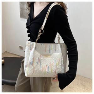 Détail du sac cabas blanc en toile avec broderie ondulée et bandoulière dorée
