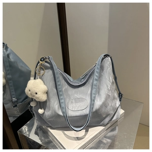 Close-up of light blue pleated tote bag featuring cloud pendant and brand label detail