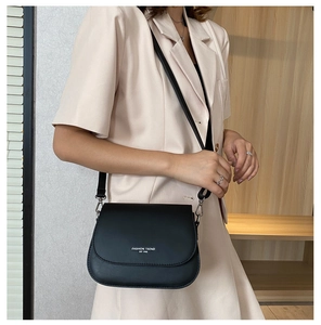 Detail of black matte saddle bag featuring white Fashion Trend typography and silver hooks