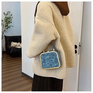 Detail van blauwe zeshoekige leren tas met gouden metalen rand en kettingriem
