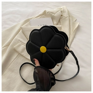 Detail of a black flower-shaped shoulder bag with yellow center buckle on a blazer