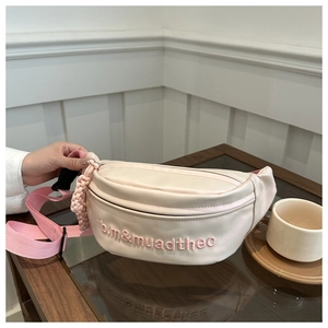 Detail of a minimalist cream waist bag featuring pink embroidery and adjustable strap
