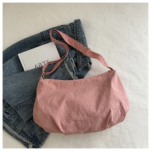 Detail of dusty rose nylon crossbody bag showing the adjustable strap on a white texture