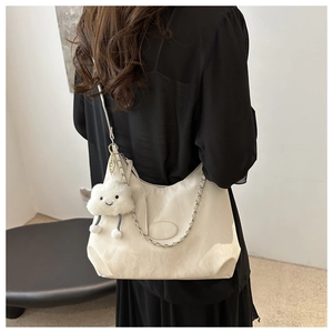 Cream hobo shoulder bag with silver chain and plush cloud charm on a model's shoulder