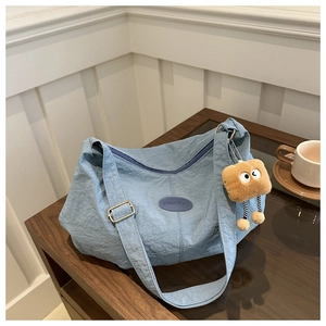 Detail of blue textured hobo bag featuring fashion logo and a cute plush charm