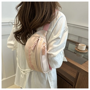 Close-up of pink crossbody bag with letter embroidery and woven zipper tassel detail