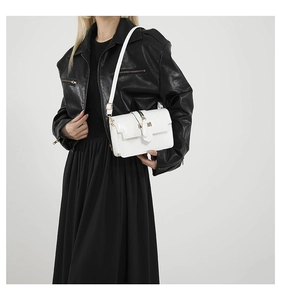 Close-up of a white leather crossbody bag with gold buckle on a stylish model in black