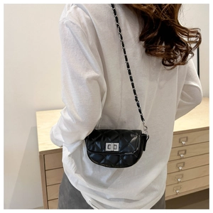 Mini sac bandoulière matelassé noir avec fermoir argenté porté par un mannequin en intérieur