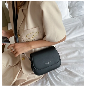 Close-up of black matte saddle bag with silver hardware on a cream blazer outfit