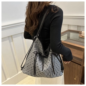 Detail of grey heart-pattern tote bag with vertical zippers and bow ribbon accents