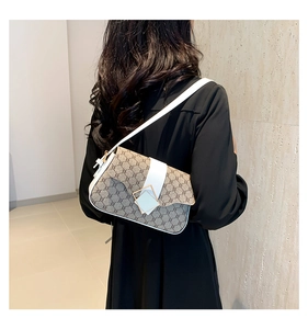 Détail du sac bandoulière vintage avec motif monogramme café et bordure en cuir blanc