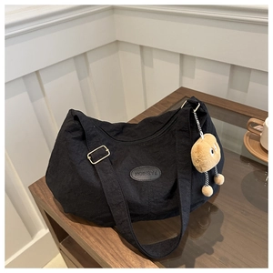 Detail of black crescent shoulder bag with crinkle texture and cute biscuit plush charm