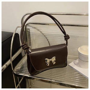 Détail d'un sac en cuir marron avec une boucle noeud argentée et des nœuds sur la lanière