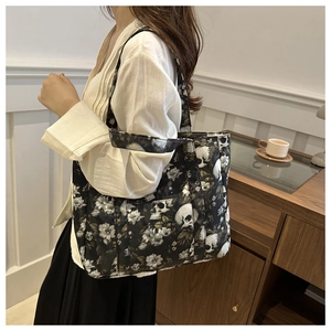 Detail of a black tote bag featuring vintage white floral and skull patterns