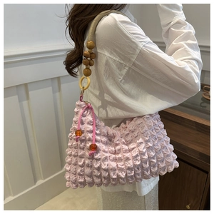 Détail du sac rose à texture bulles avec bandoulière tressée et perles en bois