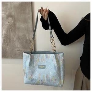 Gros plan d'un cabas en cuir bleu clair avec logo embossé et broderie ondulée colorée