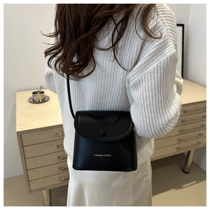 Detail of minimalist black leather crossbody bag with gold Fashion & Bags lettering