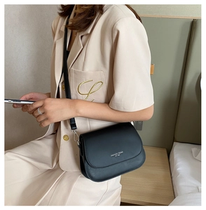 Detail of black saddle bag featuring fashion letter print and matte leather texture