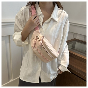 Pink crossbody waist bag with embroidered letters and adjustable strap on a model
