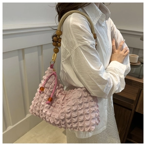 Vue détaillée du sac à main plissé rose avec poignée en corde beige et perles en bois