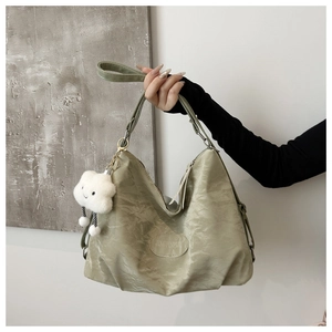 Detail of sage green tote bag with wrinkled texture and fluffy cloud charm accessory