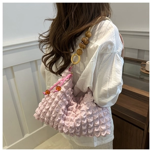 Détail du sac nuage froncé rose avec perles en bois décoratives sur une chemise blanche