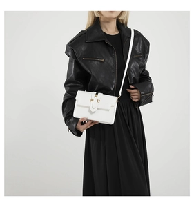 Detail of white square crossbody bag showing sleek leather texture and gold buckle hardware